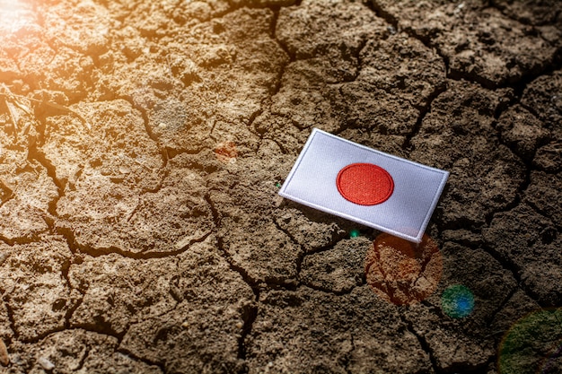 Bandera de Japón en tierra agrietada abandonada.