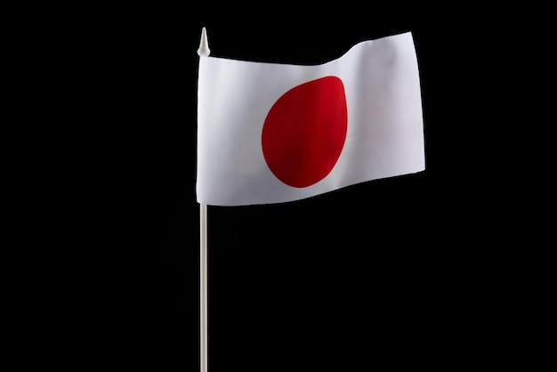 La bandera japonesa sobre un fondo negro desarrollándose y volando en el viento