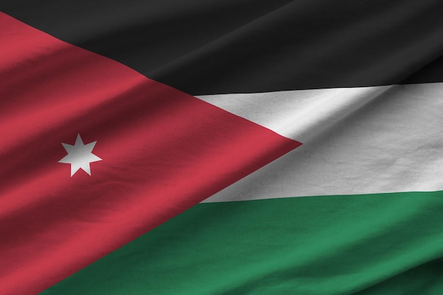 Bandera jordana con grandes pliegues ondeando de cerca bajo la luz del estudio en el interior Los símbolos y colores oficiales en la pancarta
