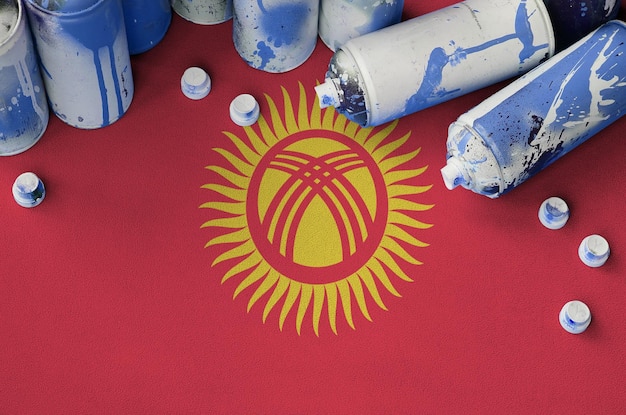 Bandera de Kirguistán y pocas latas de aerosol usadas para pintar graffiti Concepto de cultura de arte callejero