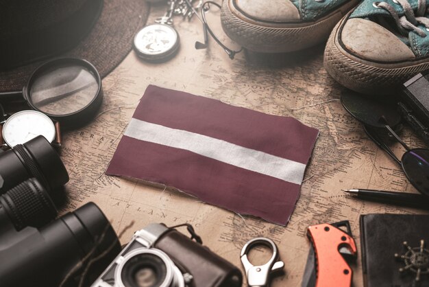 Bandera de Letonia entre los accesorios del viajero en el viejo mapa vintage. Concepto de destino turístico.