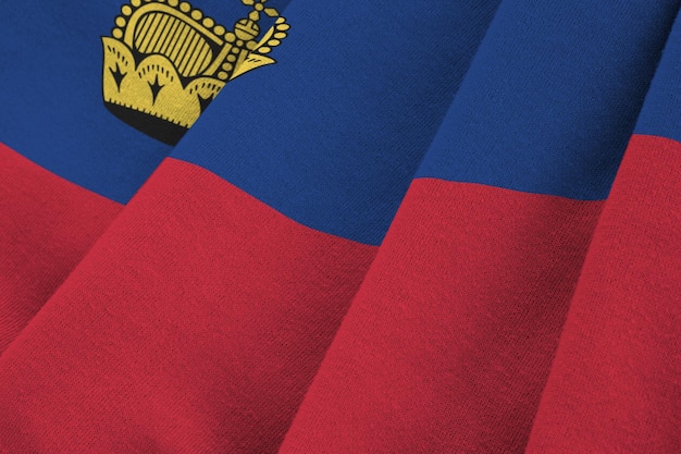 Bandera de Liechtenstein con grandes pliegues ondeando de cerca bajo la luz del estudio en el interior Los símbolos y colores oficiales en la pancarta