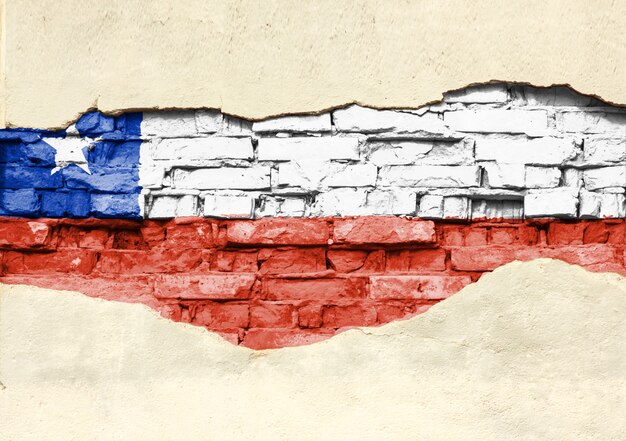 Bandera nacional de Chile sobre un fondo de ladrillo. Pared de ladrillo con yeso, fondo o textura parcialmente destruidos.