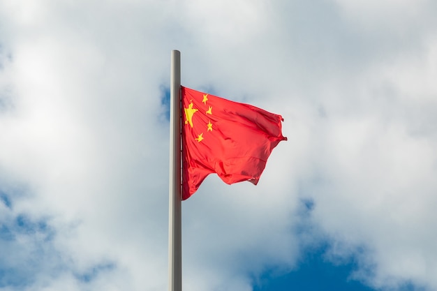La bandera nacional de China ondeando contra un cielo nublado