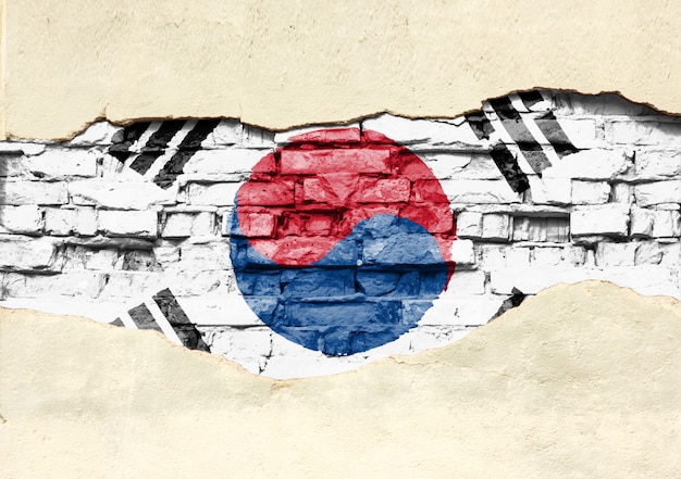 La bandera nacional de Corea del sur sobre un fondo de ladrillo. Pared de ladrillo con yeso parcialmente destruido, fondo o textura.