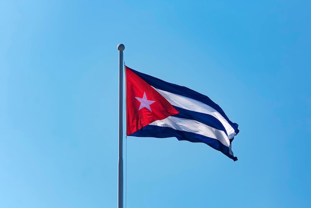 Bandera Nacional de Cuba en asta de bandera frente a cielo azul