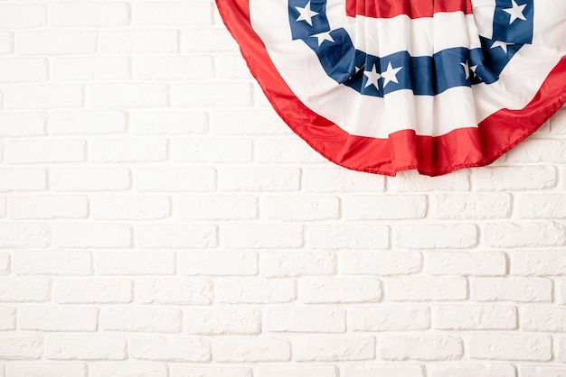 Bandera nacional de Estados Unidos sobre fondo de pared de ladrillo blanco con espacio de copia