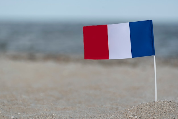 Bandera nacional de Francia en la arena del mar