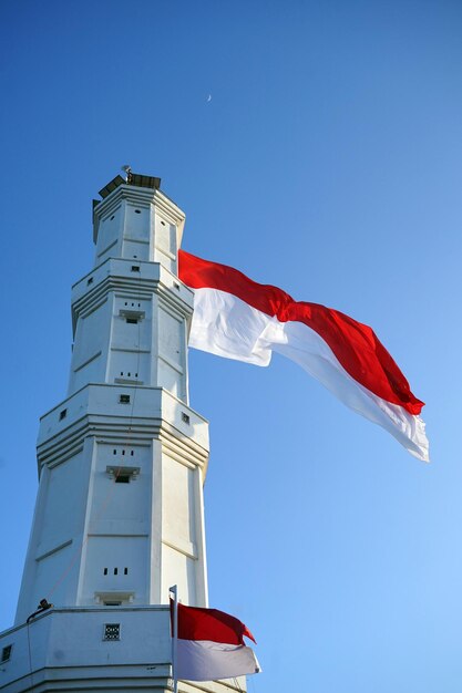 Foto bandera nacional indonesia en el faro con fondo de cielo azul