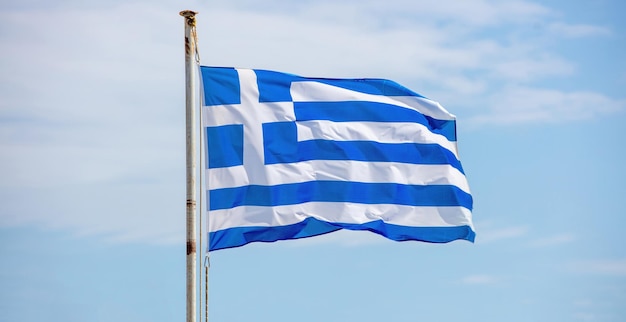 Bandera oficial nacional de Grecia en azul y blanco en asta de bandera oxidada ondeando en la isla de las Cícladas de viento