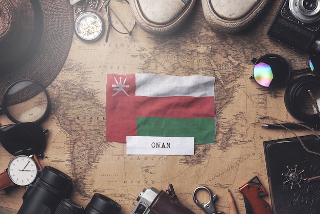 Bandera de Omán entre los accesorios del viajero en el viejo mapa vintage. Tiro de arriba