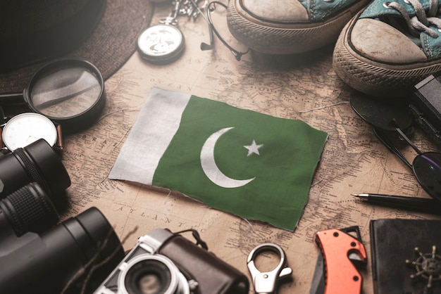 Bandera de Pakistán entre los accesorios del viajero en el viejo mapa vintage. Concepto de destino turístico.