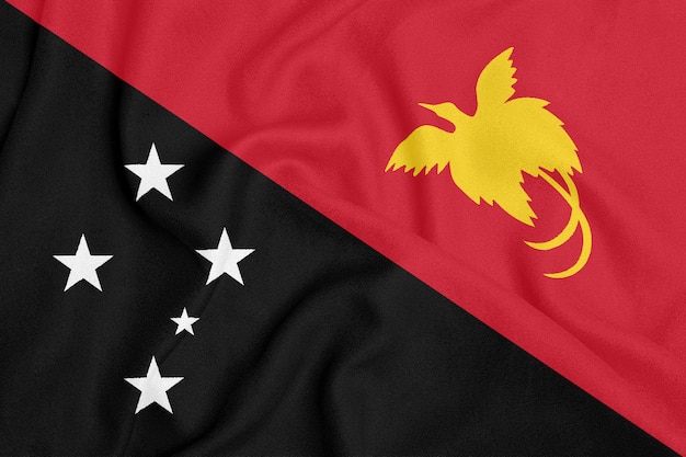 Bandera de Papua Nueva Guinea sobre tela con textura. Símbolo patriótico