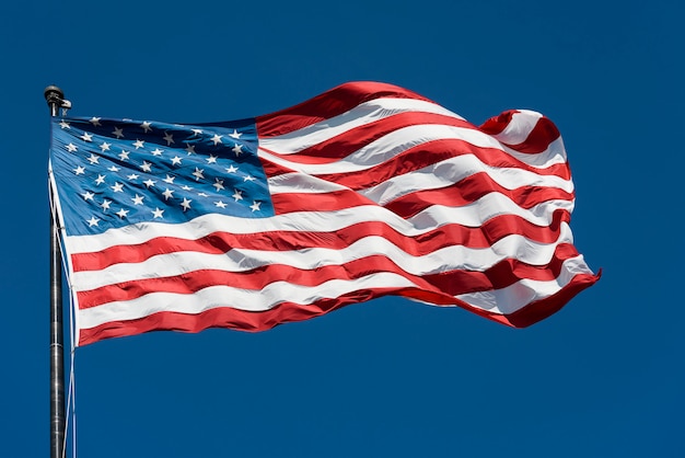 Bandera patriota americana en el cielo azul por día soleado.