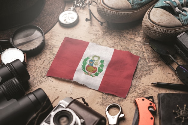 Bandera de Perú entre los accesorios del viajero en el viejo mapa vintage. Concepto de destino turístico.