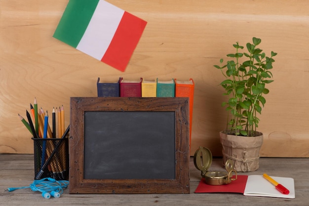 Bandera de pizarra en blanco de la cancillería de libros de Italia sobre mesa y fondo de madera