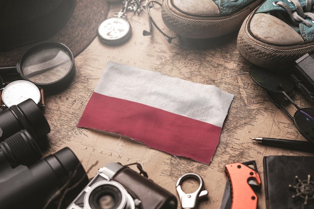 Bandera de Polonia entre los accesorios del viajero en el viejo mapa vintage. Concepto de destino turístico.