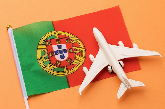 Bandera portuguesa y avión de juguete sobre un fondo coloreado, concepto sobre el tema de viajar a Portugal