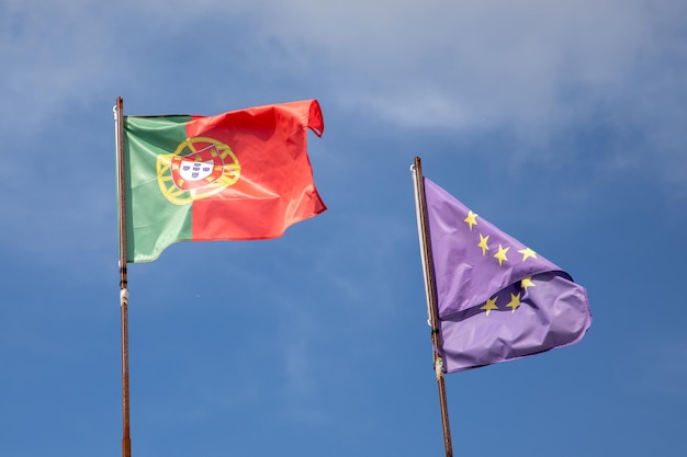 Bandera portuguesa y de la ue ondeando sobre el cielo europeo azul nube