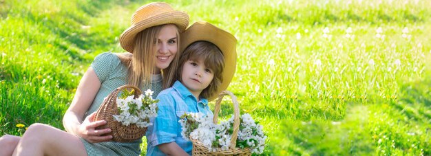 Bandera de primavera. Feliz día de la madre con su hijo en un picnic. Madre de familia con niño sentado en el césped en el parque.