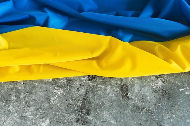 Foto bandera de raso ucraniana bandera de textura de tela ondeante de ucrania bandera real sobre fondo gris concreto