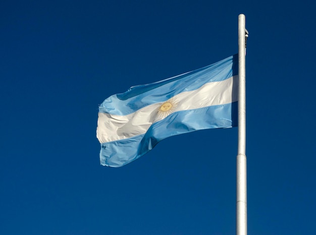 bandera de la República Argentina volando sobre el cielo azul