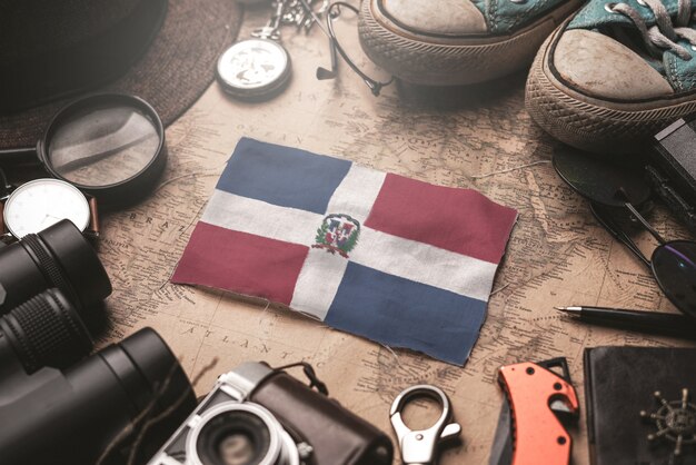 Bandera de República Dominicana entre los accesorios del viajero en el viejo mapa vintage. Concepto de destino turístico.
