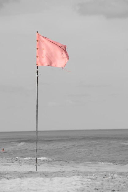 Foto bandera roja en la orilla del mar que indica que está prohibido bañarse