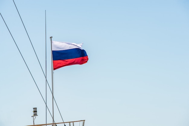 Bandera rusa en el mástil de un barco en el agua