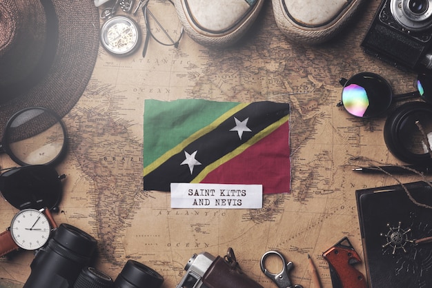 Bandera de Saint Kitts y Nevis entre los accesorios del viajero en el mapa antiguo vintage. Tiro de arriba