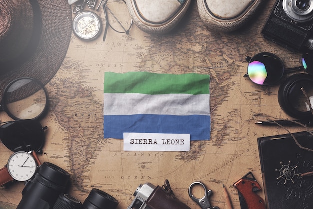 Foto bandera de sierra leona entre los accesorios del viajero en el mapa antiguo vintage. tiro de arriba