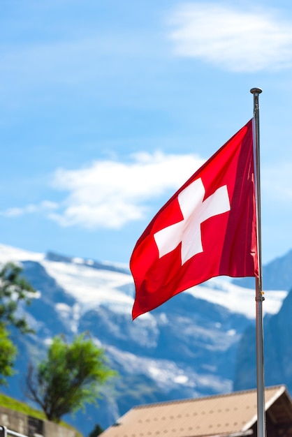Bandera suiza contra las montañas de los Alpes Disparo vertical con un enfoque selectivo