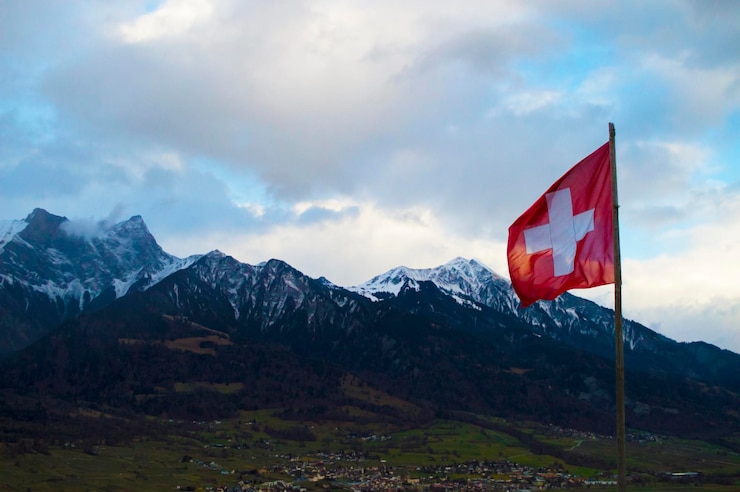 Foto bandera suiza en el fondo de las montañas alpinas