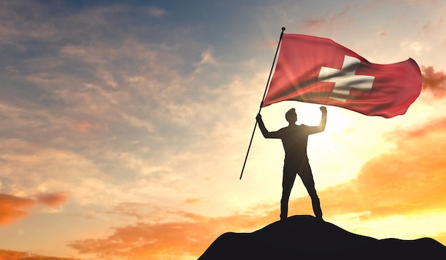 Bandera suiza ondeada por un hombre que celebra el éxito en la cima de una montaña 3D Rendering