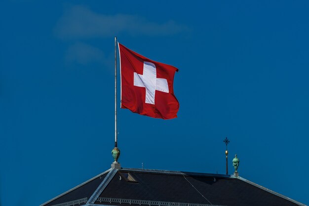 Bandera suiza ondeando en el viento contra un cielo azul