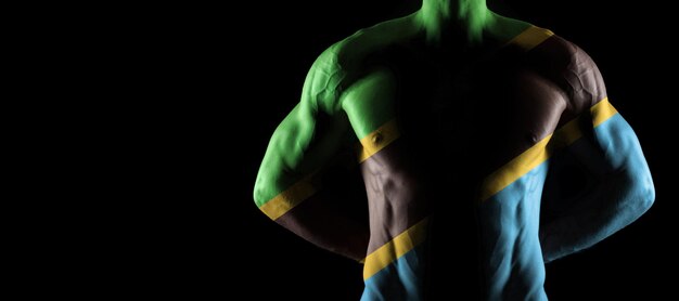 Bandera de tanzania en torso masculino musculoso con abs, fondo negro