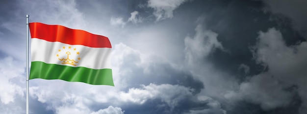 Bandera de Tayikistán en un cielo nublado