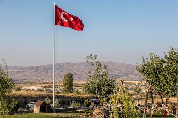 Bandera turca cerca del horizonte en Goreme Capadoci Ciudad turística con casas en Capadocia