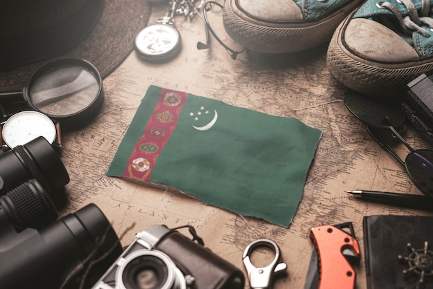 Bandera de Turkmenistán entre los accesorios del viajero en el viejo mapa vintage. Concepto de destino turístico.