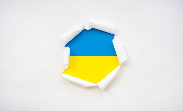 La bandera de Ucrania bajo el papel rasgado como concepto de mirar los acontecimientos del mundo rasgado