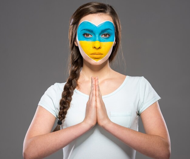 Bandera de Ucrania pintada en la cara de la mujer hermosa joven.