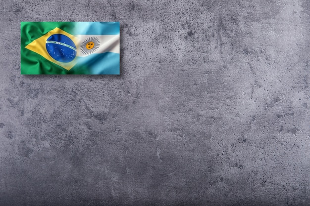 Banderas de Brasil y Argentina sobre fondo de hormigón.