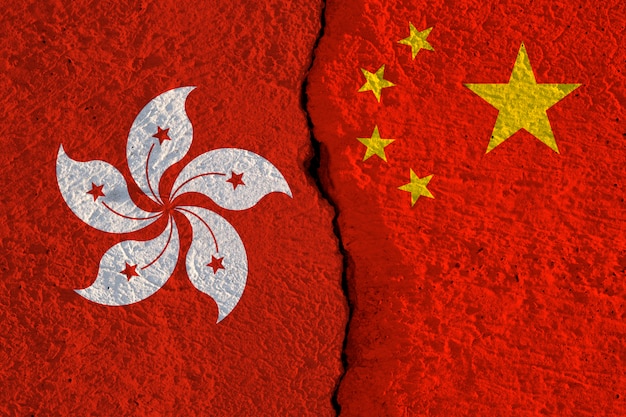 Las banderas de China y Hong Kong imprimen la pantalla en la pared agrietada.