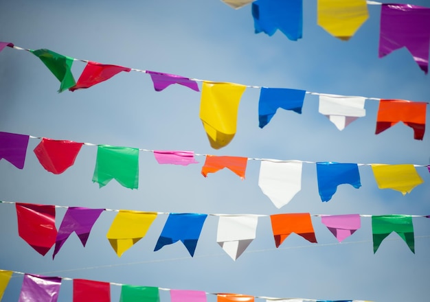 Foto banderas de diferentes colores colgando de una cuerda decoración de sao joao contra el cielo azul