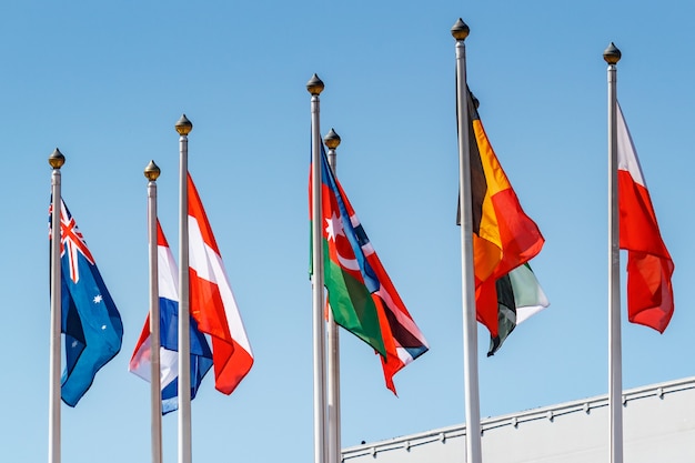 Foto banderas de diferentes países contra el cielo azul en la luz del sol
