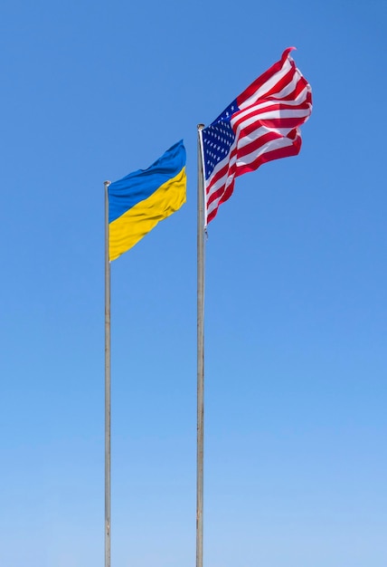 Las banderas de Estados Unidos y Ucrania ondean en el viento contra el cielo azul