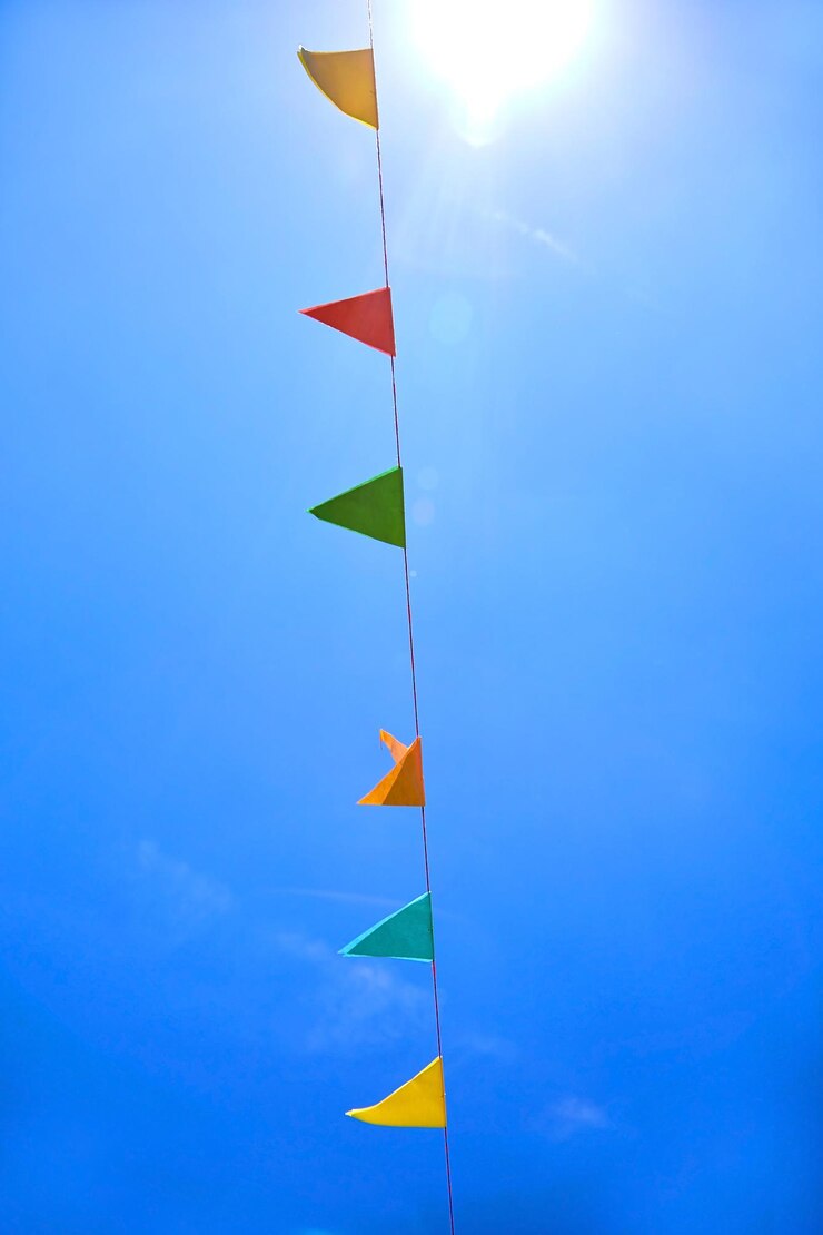 Banderas del festival de papel triangular multicolor sobre fondo de cielo azul Fiesta al aire libre Ambiente festivo