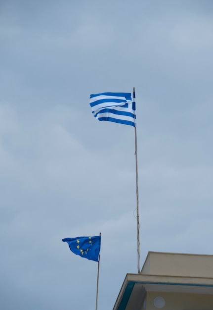 Banderas griegas y de la UE ondean contra el fondo de un cielo tormentoso y nubes