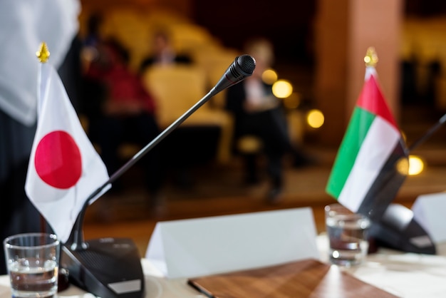Banderas japonesas y emiratíes en una mesa con micrófono en una conferencia internacional
