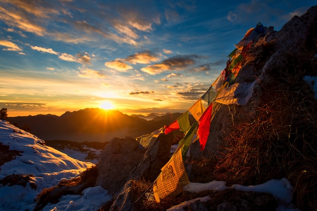 Banderas de oraciones tibetanas en las montañas con los colores de una cálida puesta de sol